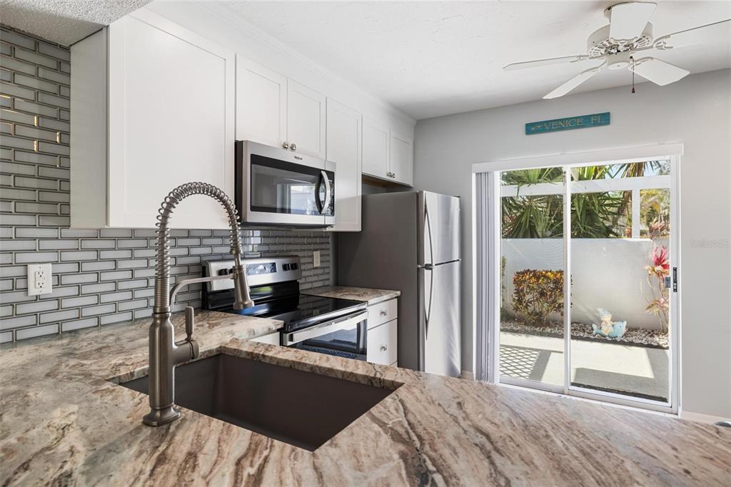 276 Cerromar Way South, Unit 60 Venice, FL 34293 - Photo 6 of 31 a kitchen with a refrigerator a stove a sink cabinets and a dining table