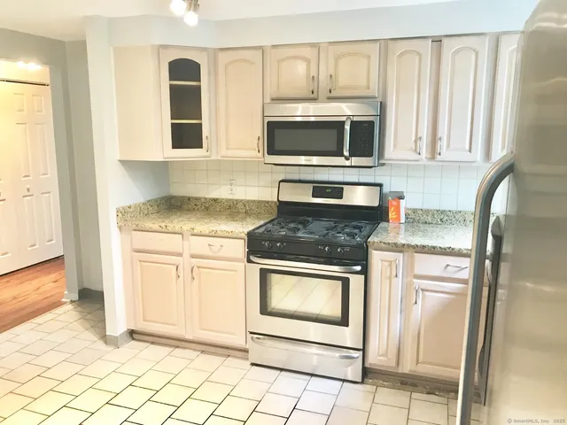 a kitchen with stainless steel appliances granite countertop a stove microwave and refrigerator