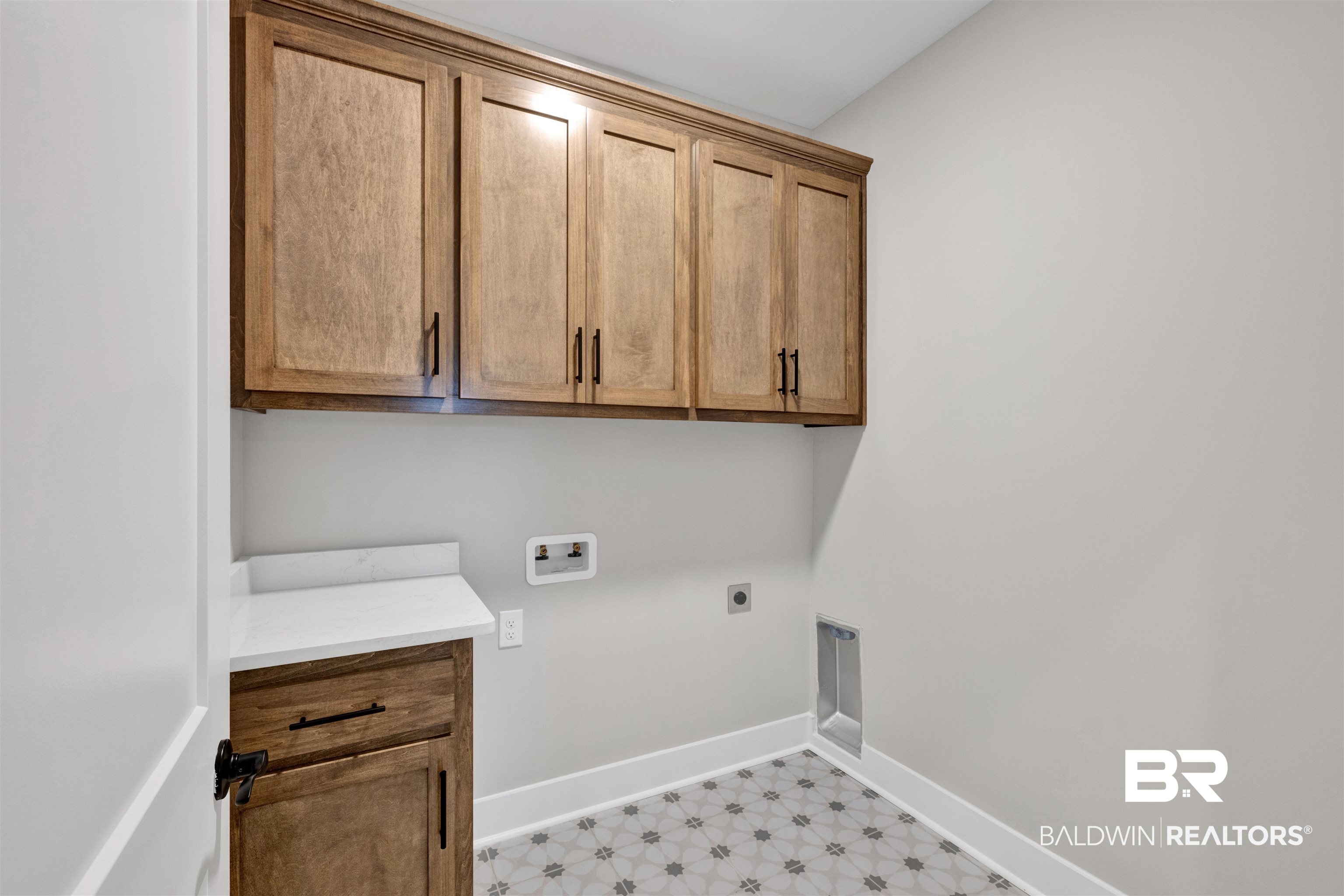 27371 Patch Pl Loop Daphne, AL 36526 - Photo 48 of 63 Laundry area featuring wood-finish cabinetry, a white countertop, and patterned floor tiling
