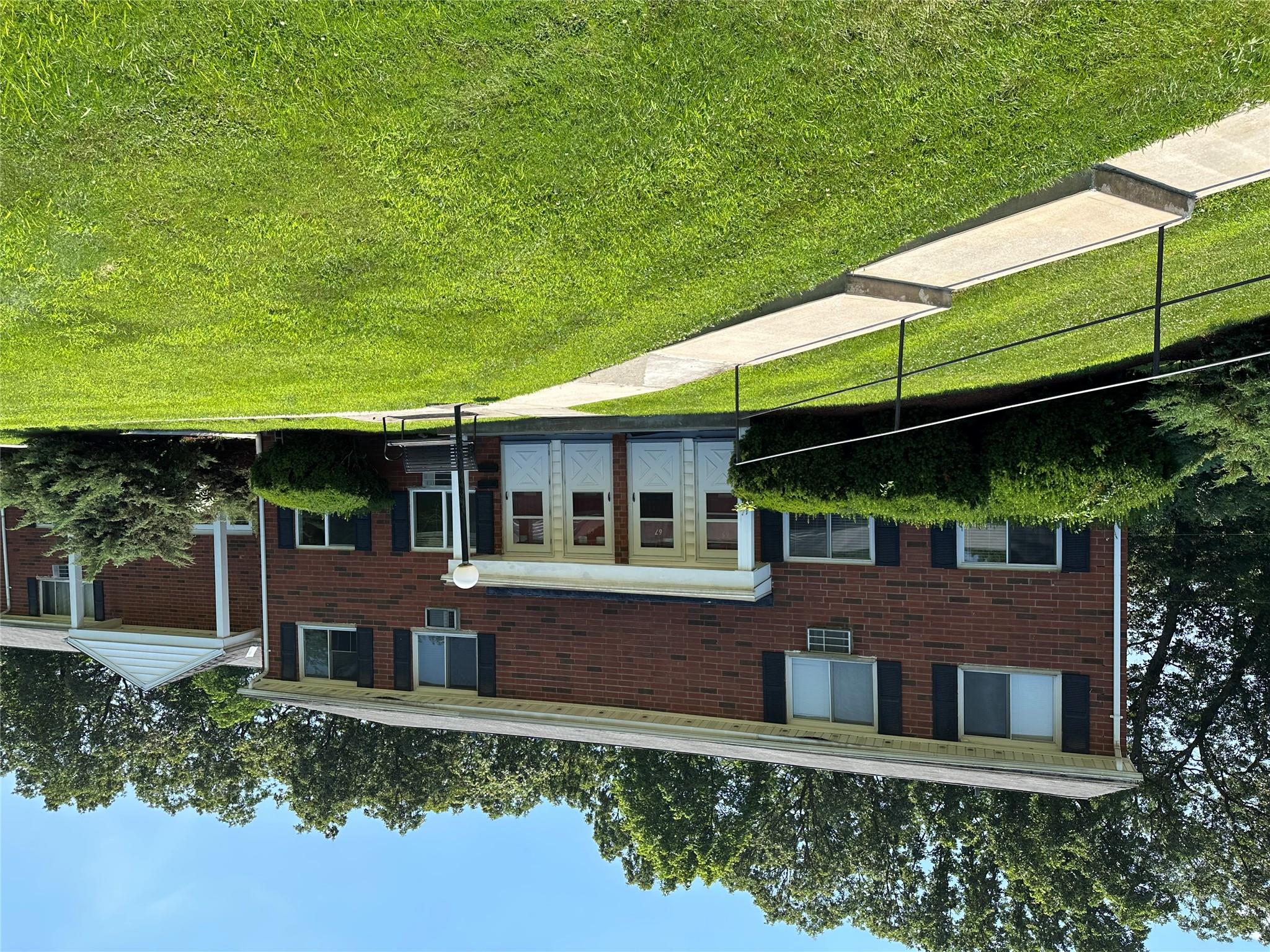 a view of a house with a yard and a large tree