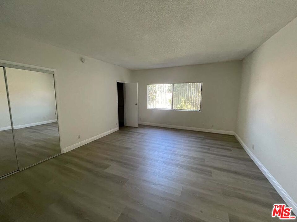 15033 Sherman Way, Unit E Van Nuys, CA 91405 - Photo 1 of 2 an empty room with wooden floor and window