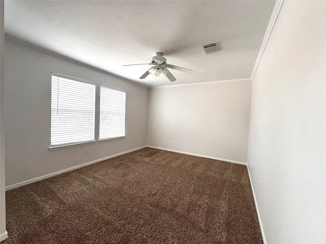 an empty room with windows and chandelier fan