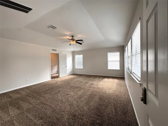 en empty room with windows and ceiling fan