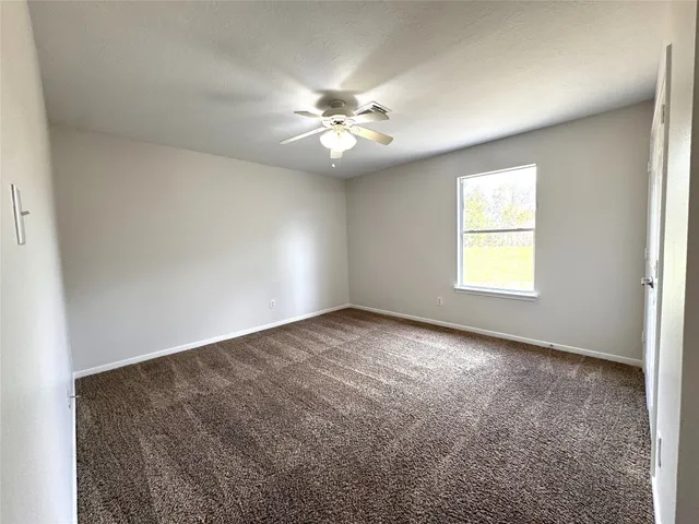 an empty room with windows and fan