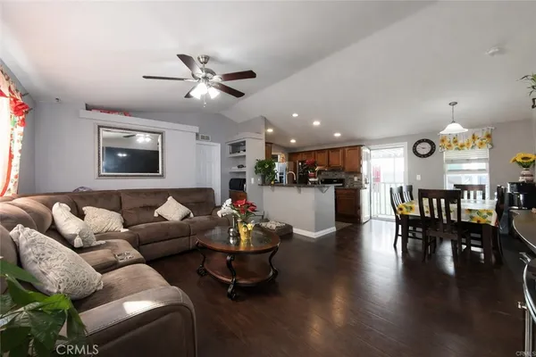 a living room with furniture kitchen view and a wooden floor