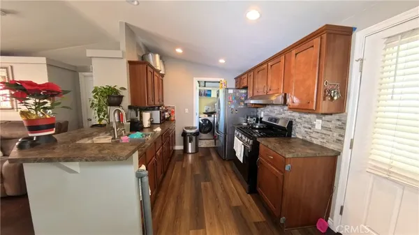 a kitchen with stainless steel appliances granite countertop sink stove refrigerator and cabinets
