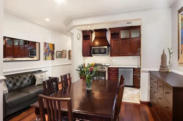 a kitchen with stainless steel appliances granite countertop a stove top oven a sink a dining table and chairs