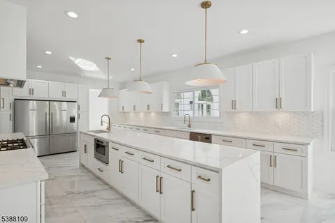 a kitchen with stainless steel appliances granite countertop a sink a oven a refrigerator and white cabinets