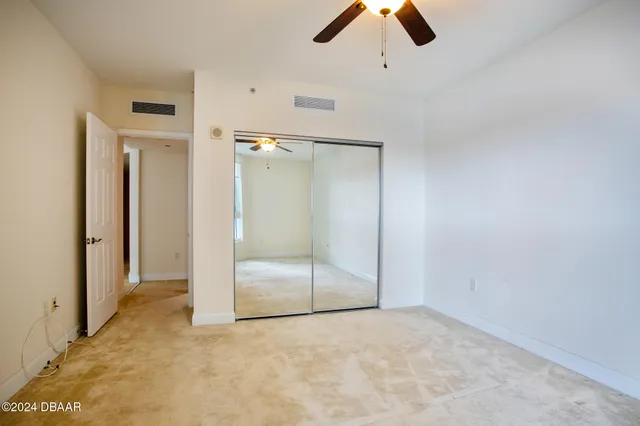 an empty room with ceiling fan and window