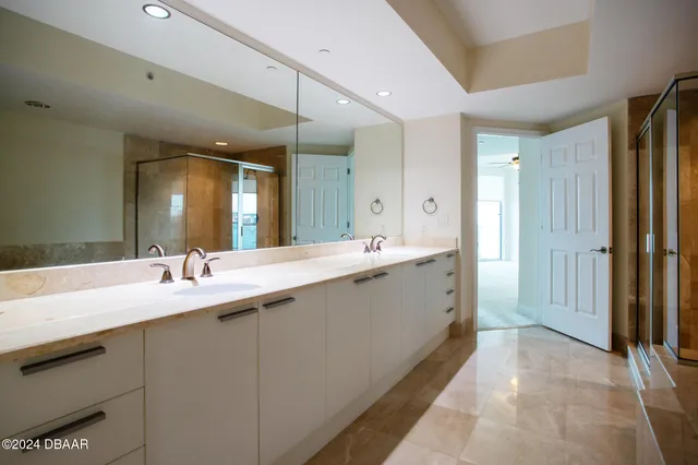 a spacious bathroom with a double vanity sink a large mirror and a bathtub