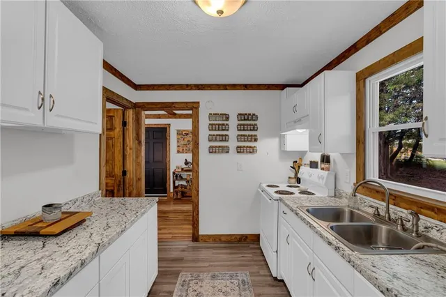 a kitchen with granite countertop kitchen island stainless steel appliances a sink stove and cabinets