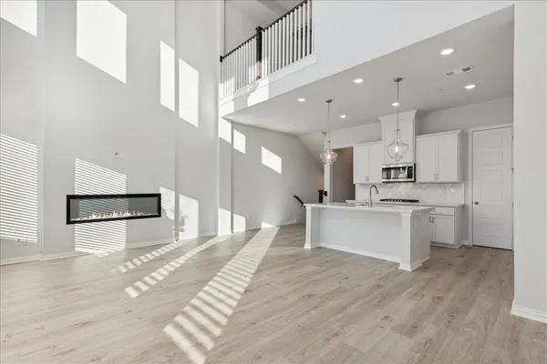 a large kitchen with stainless steel appliances kitchen island a refrigerator a sink dishwasher a stove and white cabinets with wooden floor