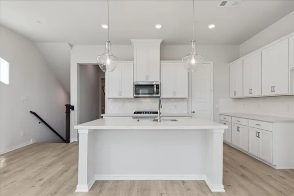 a kitchen with kitchen island stainless steel appliances a sink a stove a microwave and cabinets