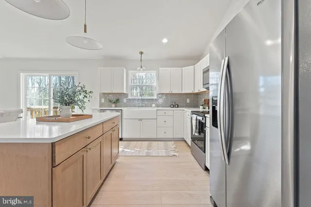 a kitchen with stainless steel appliances granite countertop a sink a stove a refrigerator a center island with cabinets and wooden floor