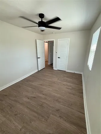an empty room with a ceiling fan and window