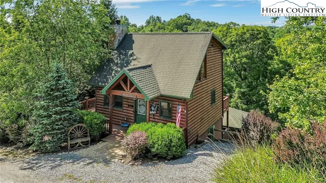 a view of a house with a small yard and a large tree