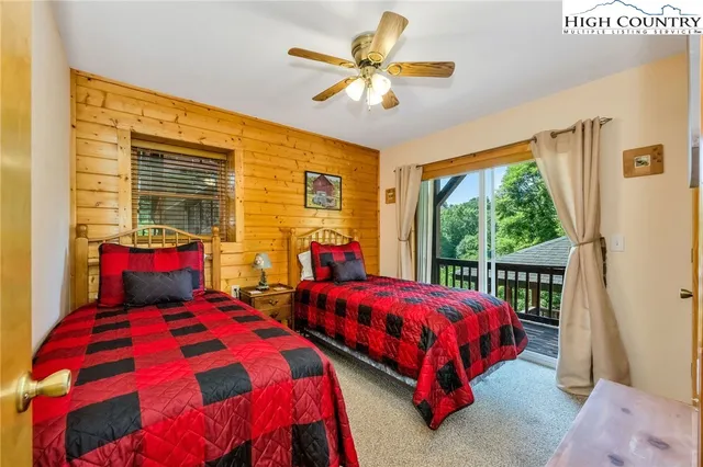 a bedroom with two beds and next to a window