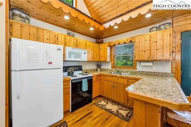 a kitchen with a refrigerator a stove a sink dishwasher and wooden cabinets