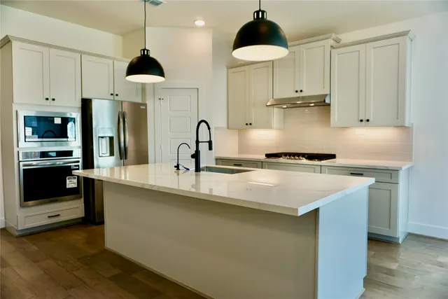 a kitchen with stainless steel appliances a sink a stove a refrigerator and cabinets
