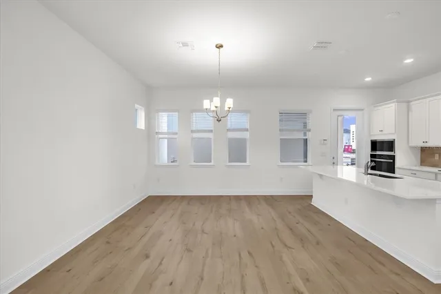 an empty room with wooden floor and kitchen view