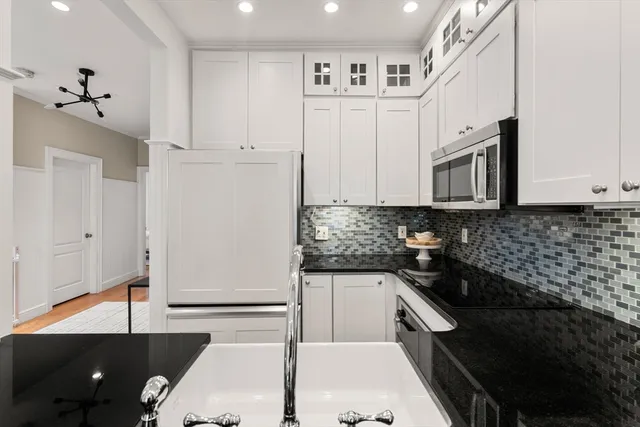 a kitchen with granite countertop white cabinets and stainless steel appliances