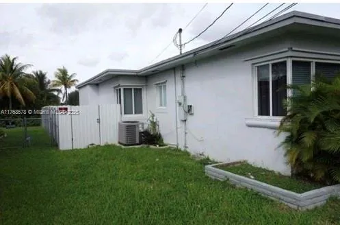 a view of a house with a yard plants and a large tree