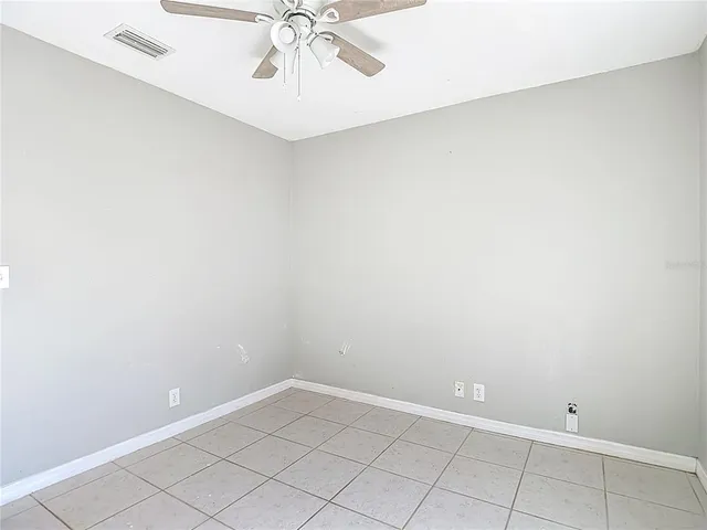 an empty room with a chandelier fan and glass door