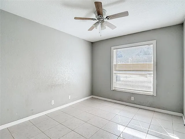 an empty room with chandelier fan and windows