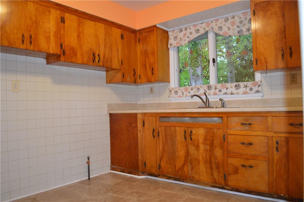 The kitchen features wood cabinetry, a gas line for the stove and a double window overlooking the back yard and woods!