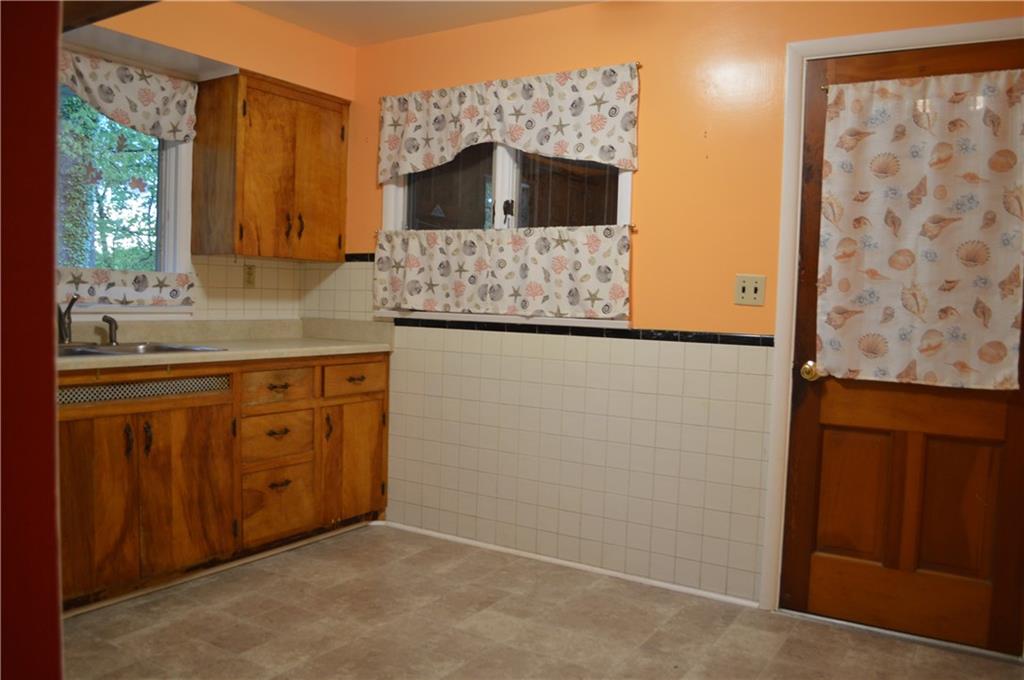 Another view of the kitchen showing the man-door direct to the garage.  Newer vinyl flooring.