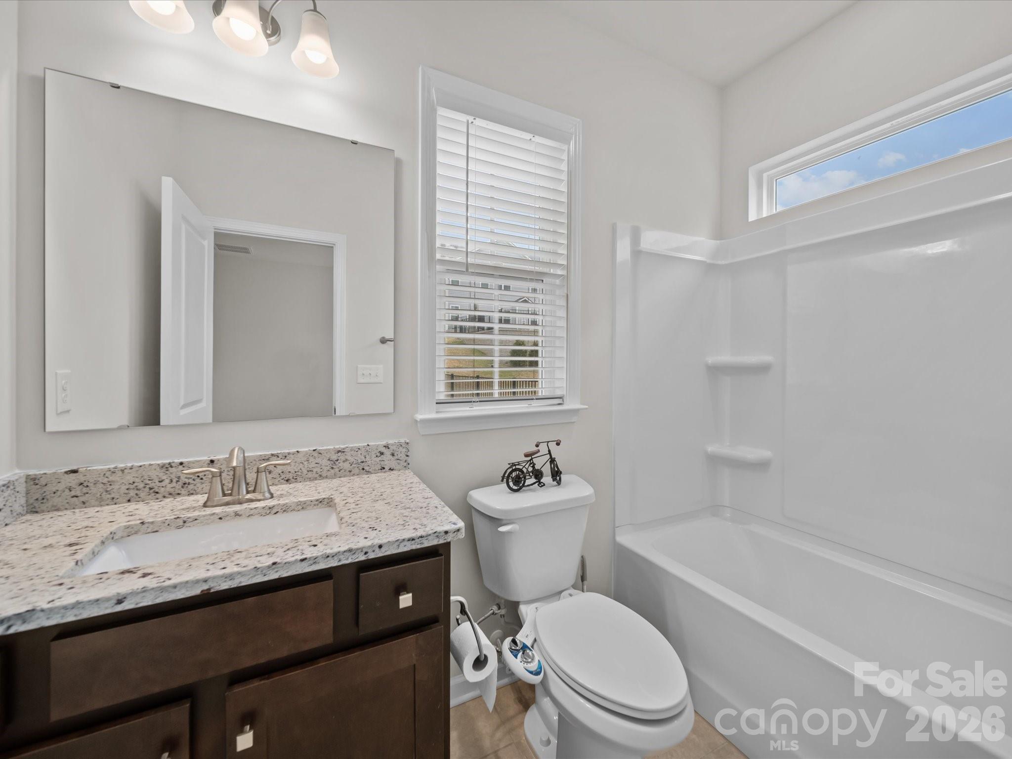 9582 Creighton Road Northwest Concord, NC 28027 - Photo 25 of 43 a bathroom with a granite countertop toilet a sink and a bathtub
