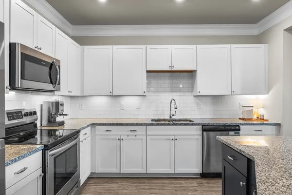 a kitchen with granite countertop white cabinets stainless steel appliances and sink
