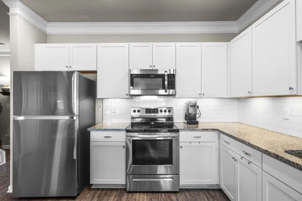 a kitchen with granite countertop a sink stove and wooden floor