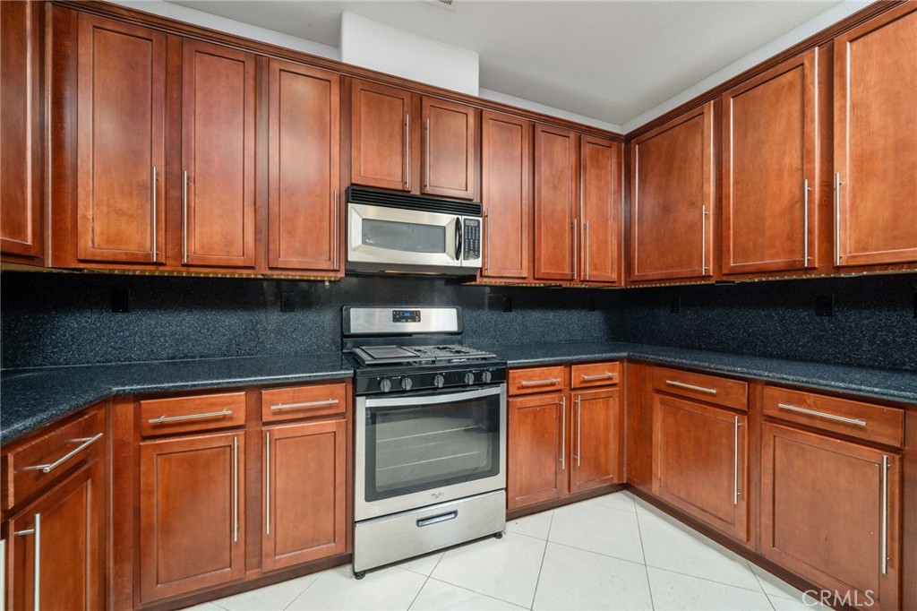 7331 Shelby Place, Unit 102 Rancho Cucamonga, CA 91739 - Photo 14 of 44 a kitchen with granite countertop wooden cabinets and a stove top oven
