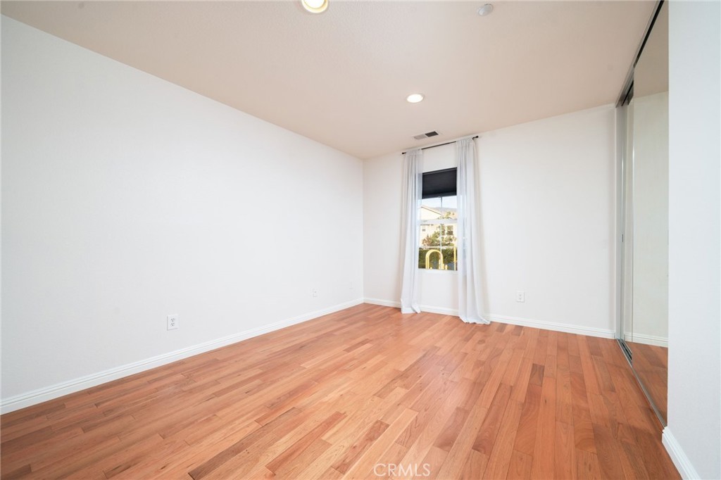 7331 Shelby Place, Unit 102 Rancho Cucamonga, CA 91739 - Photo 19 of 44 a view of an empty room with wooden floor and a window