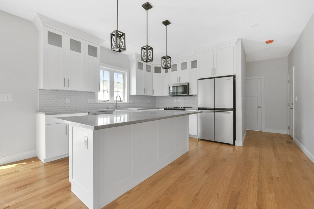 35 Roosevelt Road Dedham, MA 02026 - Photo 16 of 40 a kitchen with stainless steel appliances granite countertop a refrigerator a sink dishwasher a stove and white countertops with wooden floor