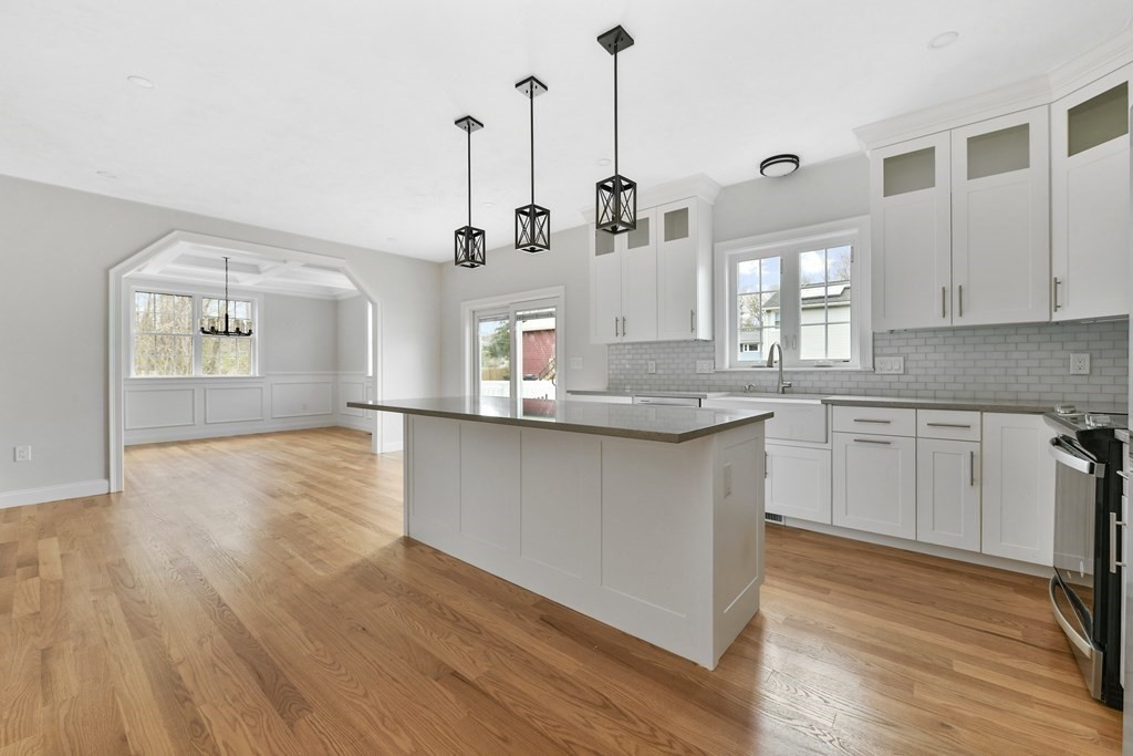 35 Roosevelt Road Dedham, MA 02026 - Photo 19 of 40 a kitchen with stainless steel appliances granite countertop a sink a stove and white cabinets with wooden floor