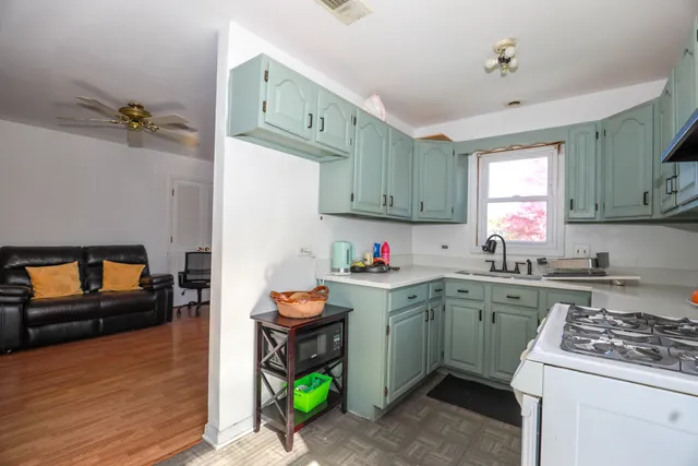 a kitchen with a sink a stove cabinets and wooden floor