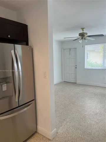 a view of a refrigerator in kitchen and an empty room