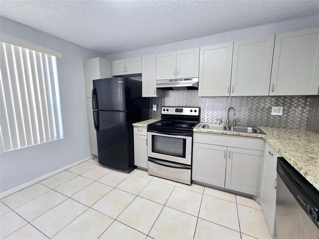 a kitchen with white cabinets and appliances