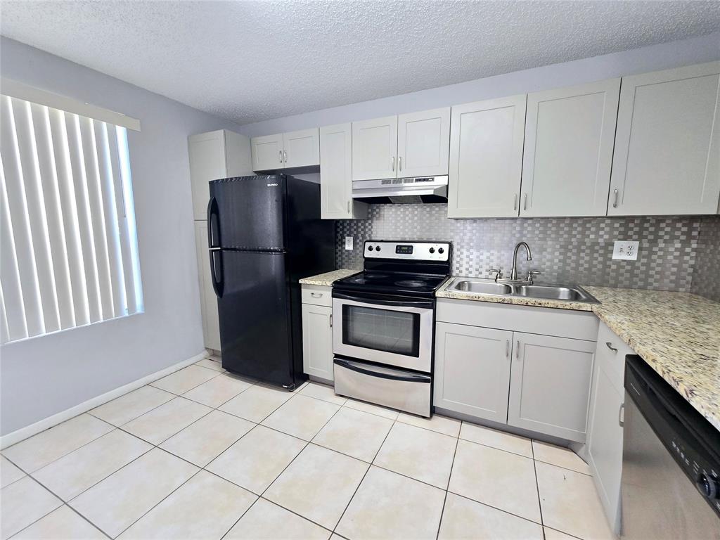 8100 Southwest 21st Court, Unit 8100 Miramar, FL 33025 - Photo 9 of 22 a kitchen with white cabinets and appliances