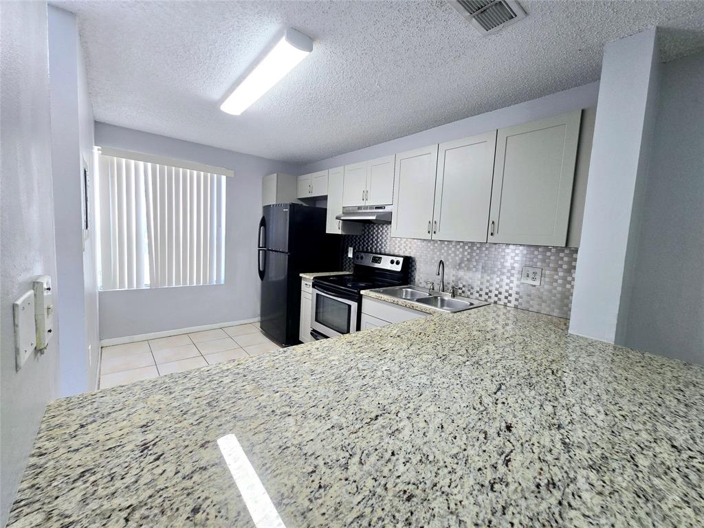 8100 Southwest 21st Court, Unit 8100 Miramar, FL 33025 - Photo 10 of 22 a kitchen with granite countertop a sink cabinets and stainless steel appliances