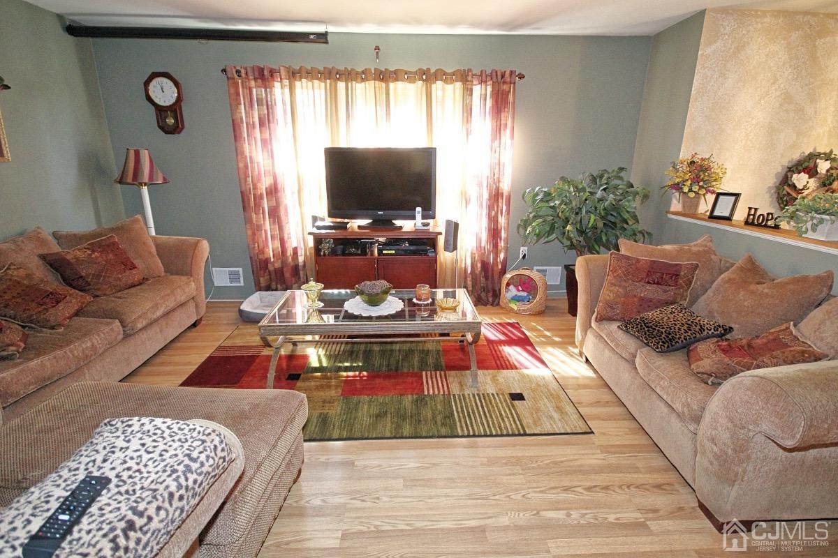 17 Higgins Road Old Bridge, NJ 08857 - Photo 5 of 30 a living room with furniture a flat screen tv and a floor to ceiling window