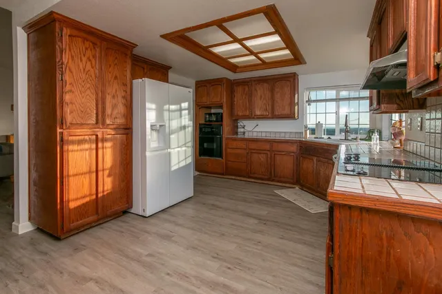 a large kitchen with stainless steel appliances granite countertop a refrigerator and a wooden cabinets