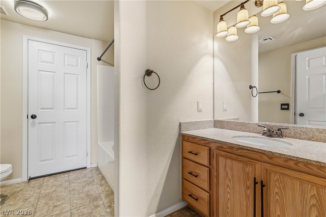 10550 West Alexander Road, Unit 2060 Las Vegas, NV 89129 - Photo 27 of 45 A well-appointed bathroom features a light-toned wood vanity with ample storage, topped by a speckled counter.