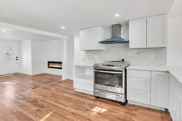 a kitchen with granite countertop a stove a sink and a white cabinets