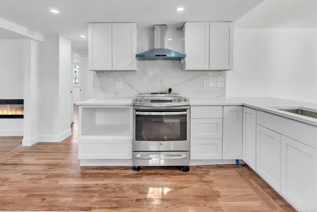 a kitchen with granite countertop a stove a sink and a refrigerator