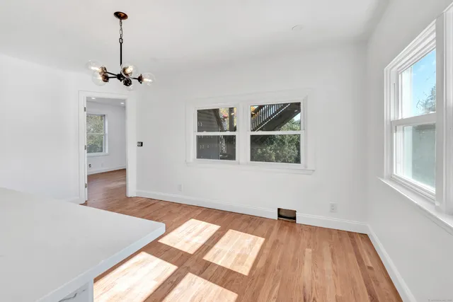 a view of an empty room with window and wooden floor