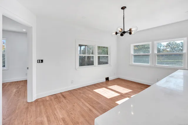 a view of an empty room with a window and wooden floor