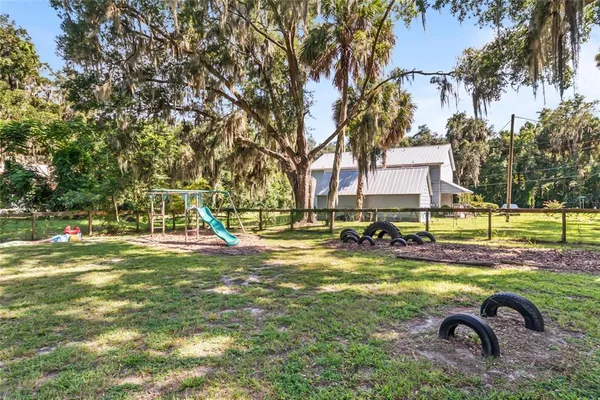 a view of backyard of house with outdoor seating and trees